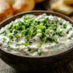 A bowl of freshly made scallion cream cheese with chopped green onions on top